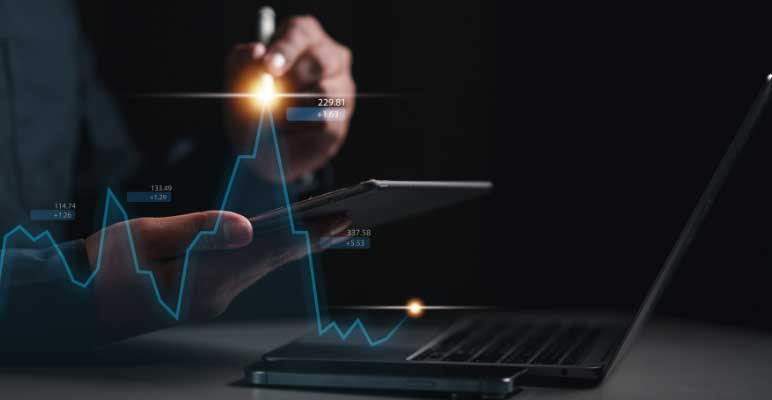 Photo of human male torso sitting in front of a desk with laptop on it. The person is holding a small flashlight that is illuminating a super imposed stock market graph.