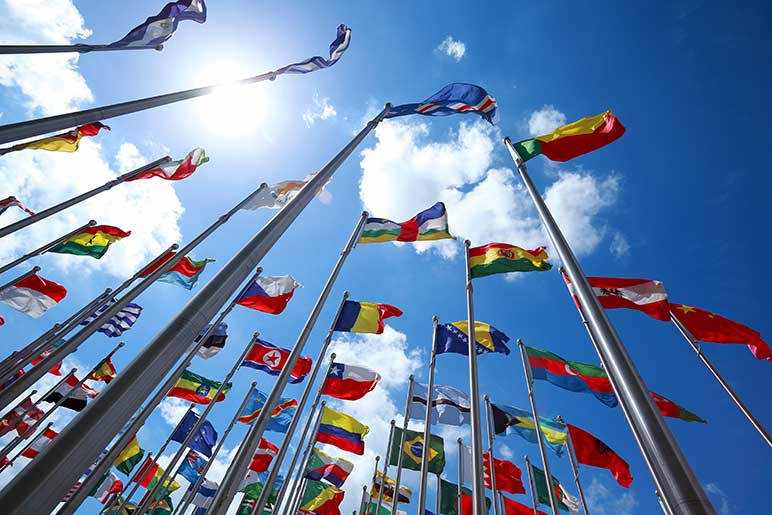 Flags of all nations of the world are flying in blue sunny sky