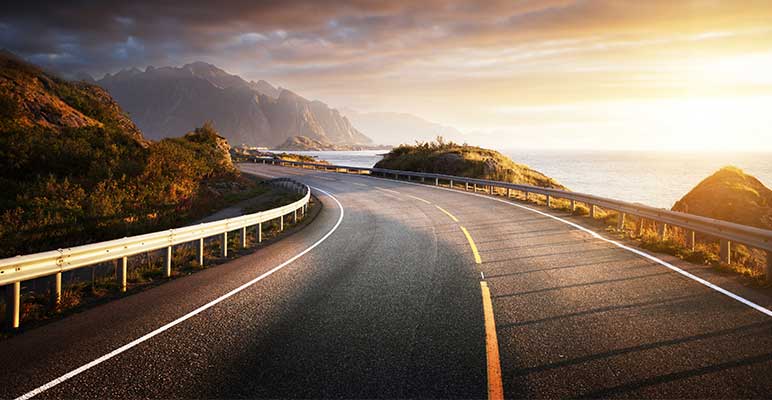 Photo of open road by the sea at sunrise.